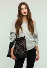 Sivá mikina s off-shoulder dizajnom, doplnená štruktúrovanou čiernou a hnedou kabelkou s leopardím vzorom, ktorá má sťahovací uzáver a rukoväte.