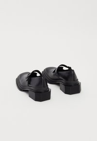 Black leather shoes with a rounded toe, low-cut sides, and a chunky rectangular heel. Features an adjustable strap for a secure fit.