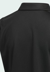 Zwarte polo met een gladde textuur, klassieke kraag en korte mouwen. De stof toont subtiele stikdetails.