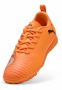 Scarpa sportiva di colore arancione brillante con tomaia texturizzata, caratterizzata da strisce gradiente e accenti del logo neri. Design con lacci e suola in gomma.