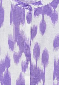 Lila und weiße gemusterte Stoffbluse mit Knopfverschluss und weicher Textur. Verfügt über unregelmäßige Flecken- und Streifenmuster.