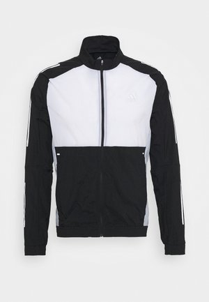 Zwart-wit jack met ritssluiting en hoge kraag, voorzien van een effen kleurvlakdesign, lichtreflecterende strepen en een geborduurd logo.