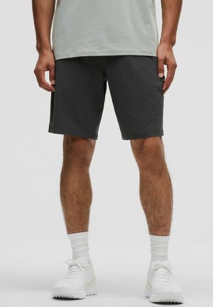 Gray athletic shorts with a smooth texture, knee-length fit, and side pockets, paired with white sneakers and socks.