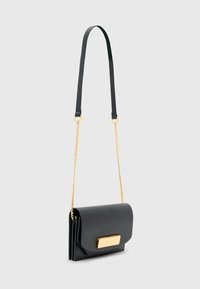Borsa a tracolla nera in pelle con dettagli in metallo dorato, chiusura a pattina e manico a catena. Tessitura liscia, forma rettangolare.