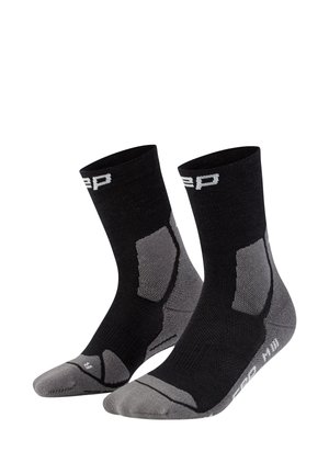 Black and gray athletic socks with cushioned areas on heel and toe, mid-calf length, and white logo text near top and foot arch.