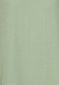 Jasnozielony materiał o gładkiej fakturze. Tkanina ma delikatny połysk i jest jednolita kolorystycznie, nie wykazując żadnych wzorów ani akcentów.