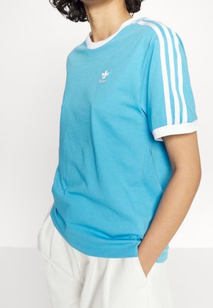 Light blue cotton t-shirt with white ribbed neckline and hem. Features three white stripes on sleeves and a small embroidered logo on chest.