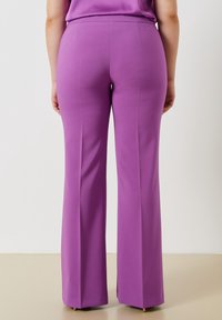 Lila utsvängda byxor gjorda av ett slätt, elastiskt tyg, med en åtsittande midja och subtila sömdetaljer bak.