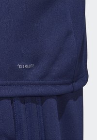 Marinblå atletisk tyg med en slät textur, med sydda sömmar och en "CLIMLITE"-logotyp, i en modern design och avsmalnad passform.