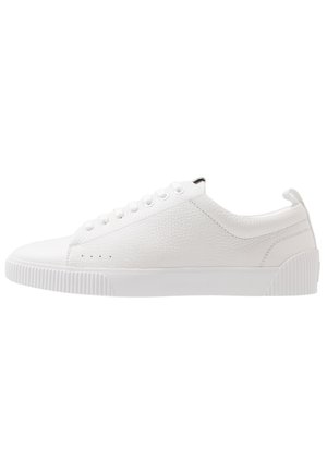 Niski biały skórzany sneaker o fakturowanej powierzchni, białych sznurowadłach oraz karbowanej gumowej podeszwie i czubku.