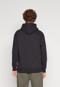 Felpa nera con cappuccio e polsini e orlo a costine, realizzata in materiale morbido, con una vestibilità comoda e tasca a marsupio sul davanti.