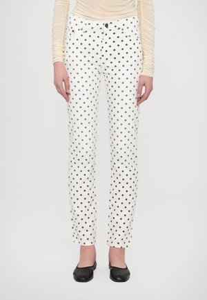Witte broek met zwarte stippen, rechte pijpen, denim materiaal, vijf zakken en knoopsluiting. Gekenmerkt door zwarte ballerina's.