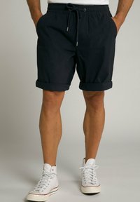 Dunkelblaue Shorts mit elastischem Bund und Kordelzug, ausgestattet mit umgeschlagenen Säumen. Tragen mit weißen High-Top-Sneakern.