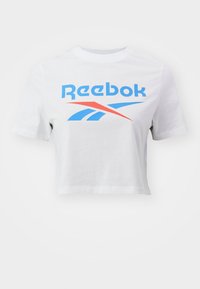Bílý zkrácený tričko s krátkými rukávy, na přední straně s grafickým designem a logem Reebok v modré a červené barvě, vyrobené z bavlny.