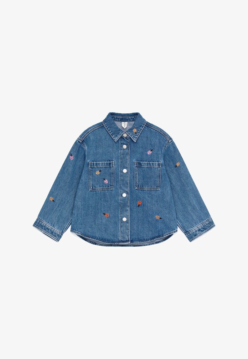 Veste en denim bleue pour enfants avec boutons, manches longues, deux poches avant et de petites coccinelles brodées colorées en décoration.