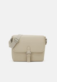 Beige Umhängetasche aus synthetischem Material mit Klappenverschluss, verstellbarem Riemen und silberfarbener Hardware-Dekoration.