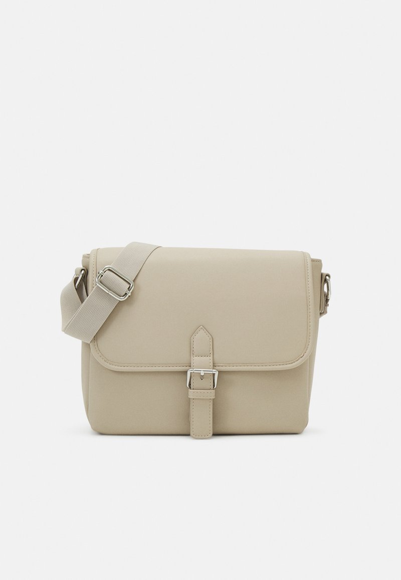 Beige Umhängetasche aus synthetischem Material mit Klappenverschluss, verstellbarem Riemen und silberfarbener Hardware-Dekoration.