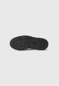 Suela de zapato de goma negra con un patrón de rodadura profundo, con el nombre de la marca "Mare O'Polo" grabado en el lateral. Texturizada para proporcionar tracción.
