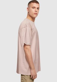 Camiseta de manga corta de color rosa claro, hecha de algodón, con un diseño relajado, cuello redondo y un diseño minimalista con costuras laterales.