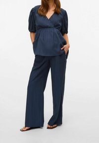 Haut rayé marine avec col en V et manches courtes bouffantes, assorti d'un pantalon large. Le tissu semble léger et texturé.