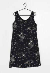 Svart ärmlös klänning med vita blommönster och geometriska mönster. Mjuk tyg med en slät textur och rundad halsringning.