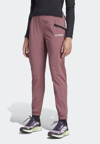 Terrex lätta, rosa byxor har en elastisk midja, sidoficka med dragkedja och avsmalnande muddar för en åtsittande look. Kombineras med träningsskor.
