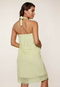 Vestido de toalla verde claro con cuello halter y lazo, tejido texturizado, cinturilla elástica y borde de encaje en el dobladillo.