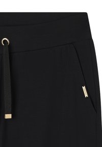 Los pantalones de chándal negros presentan un tejido texturizado, una cinturilla elástica con un ojete de metal dorado, un cordón ajustable y un bolsillo lateral con un acento dorado.