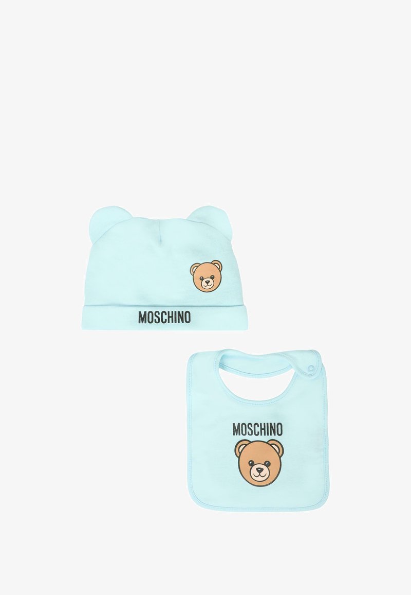 Cappellino in cotone azzurro chiaro per neonati con orecchie da orsetto e grafica stampata di un orso; bavaglino abbinato con design simile e chiusura a scatto. Entrambi presentano il logo "Moschino".