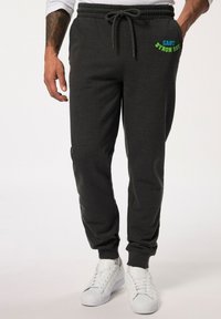 Grijze joggers met een elastische tailleband, een trekkoordsluiting en zijzakken. Kenmerken zijn de geborduurde tekst "EAST BYRON BAY" in blauw en groen.