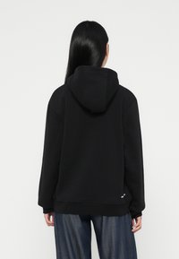 Fekete kapucnis pulóver laza szabással, bordázott mandzsettákkal és aljjal. Simító felület, oldalt jól látható márkacímkével.