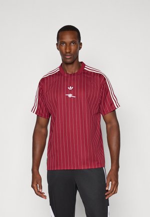 Rödrandig kortärmad polo med krage, med vita detaljer på axlarna och en broderad logotyp på bröstet.