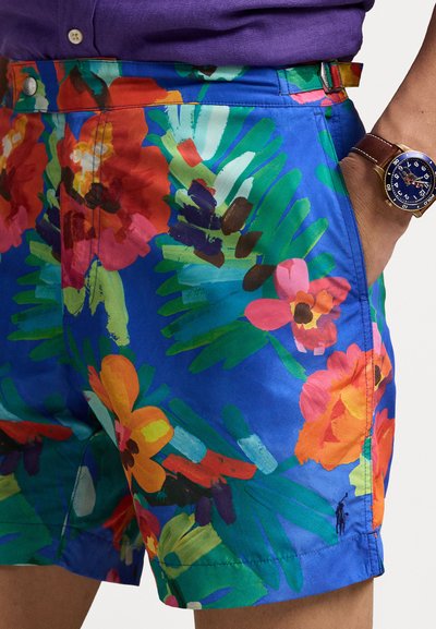 Bunte Blumen-Shorts, überwiegend blau, mit großen roten, pinken und orangefarbenen Blumen sowie grünen Blättern. Mit seitlichen Taschen und einem Knopfverschluss.