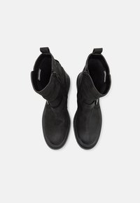 Bottes cheville noires en cuir lisse, dotées d'une fermeture éclair latérale, de deux sangles et d'une semelle texturée pour une meilleure adhérence.
