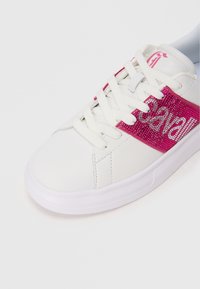 Scarpa sportiva bianca con texture liscia, caratterizzata da un pannello laterale glitterato rosa e lacci bianchi. Punta arrotondata e suola in gomma.