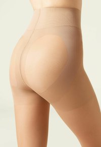 Beżowe legginsy kształtujące z wysokim stanem, gładką powierzchnią, bezszwowym designem i ciemniejszymi akcentami wokół pośladków.