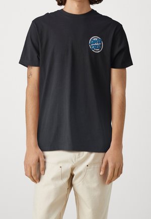 T-shirt in cotone nero con un logo circolare grafico blu e argento sul petto a sinistra. Maniche corte e vestibilità classica.