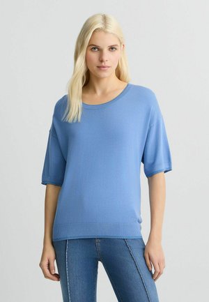 Haut bleu à manches courtes fabriqué en un tissu tricot doux, avec un col rond et des détails côtelés subtils au niveau de l'ourlet et des manches.