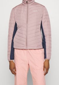 Różowa pikowana kurtka z wysokim kołnierzem, z granatowymi panelami bocznymi i przednim zamkiem błyskawicznym. Tkanina o fakturze, lekka konstrukcja.