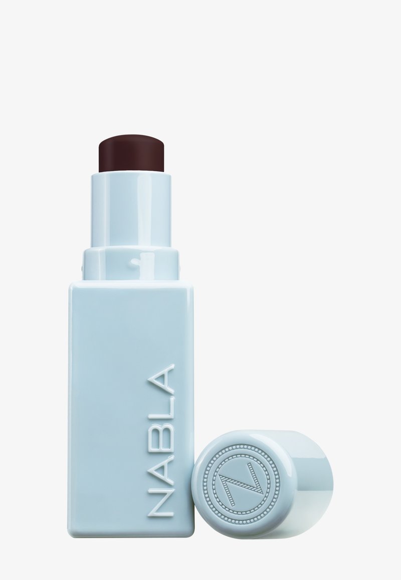 Bâton cosmétique NABLA dans un emballage bleu doux ; forme cylindrique avec un applicateur à dévissage marron foncé. Présente un logo en relief sur le capuchon.
