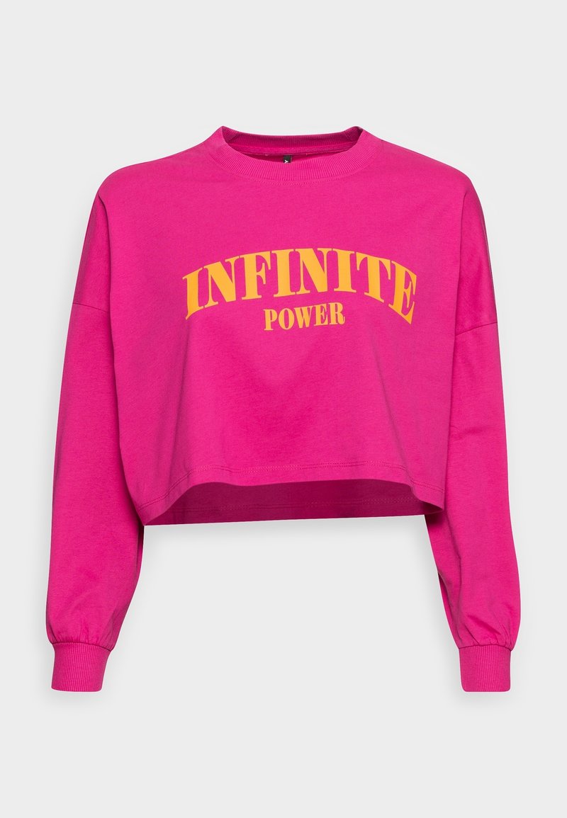 Sweat-shirt rose vif recadré à manches longues avec texte jaune "INFINITE POWER" en arc de cercle sur la poitrine.