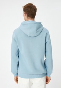 Sudadera azul claro con capucha ajustable, puños y dobladillo acanalados. Fabricada con un tejido suave de textura lisa, diseñada para la comodidad.