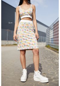 Värikäs lyhyt toppi ja kynähameyhdistelmä, jossa on ruutukuosi pastellisävyissä. Yhdistetty chunky-valkoisiin alustaviin tenniskenkiin.