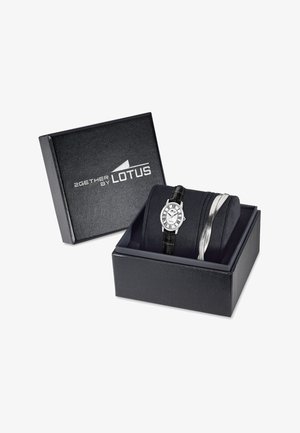 Melns ādas pulksteņu kārba, kurā atrodas sudraba tonīta pulkstenis ar apaļu ciparnīcu un melnu ādas siksniņu, kā arī sudraba rokassprādze, kārtīgi izvietota.