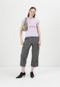 Sviesiai violetinė marškinėliai su užrašu "JUST JUICY" rožiniu blizgučiu, pilki pakraščiai kelnės su kišenėmis ir juodi smailūs aukštakulniai. Kuprinė su gy snakeskin raštu.