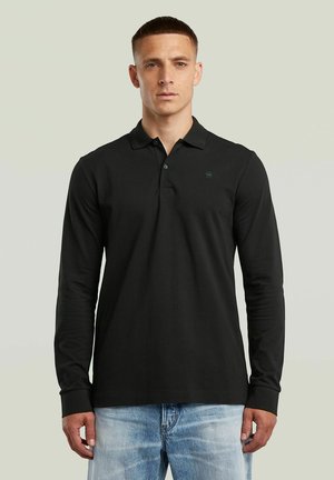 Czarna, długosleeve polo z bawełny, z kołnierzykiem, listwą guzikową i małym logo na piersiach, zestawiona z jasnoniebieskimi dżinsami.