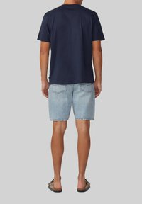 Marinefarbener Rundhals-T-Shirt, kombiniert mit hellblauen Jeansshorts. Das Shirt hat kurze Ärmel; die Shorts verfügen über Gesäßtaschen und einen lässigen Schnitt.