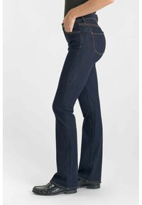 Donkerblauwe uitlopende jeans van denim, met contrasterende stiksels, vijf zakken en een mid-rise taille. Gladde textuur en aansluitend ontwerp.