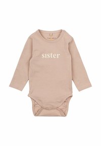 Långärmad bodysuit i ljusrosa bomull med rund halsringning och tryckknappar vid axeln. "Syster" tryckt i vitt fram. Mjuk textur.
