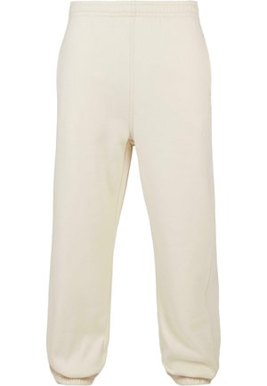 Pantaloni della tuta color crema realizzati in tessuto morbido, con vita elasticizzata e polsini a costine, dettagli sulle cuciture laterali.